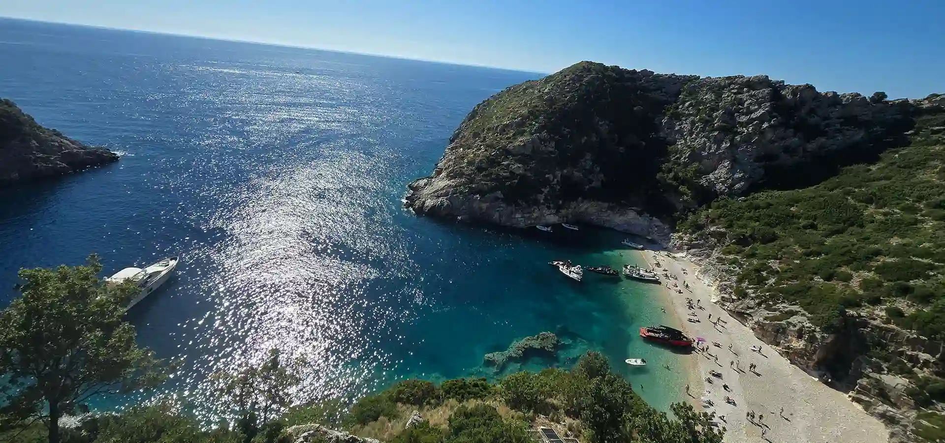 Aerial view of Grama Bay with turquoise water enclosed by dramatic limestone cliffs, Karaburun Peninsula Albania