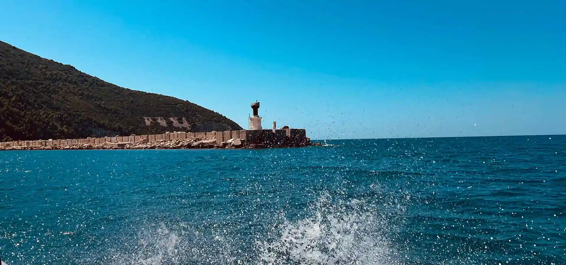 View of Sazan Island from the sea with green hillside and turquoise Ionian water, Bay of Vlore Albania