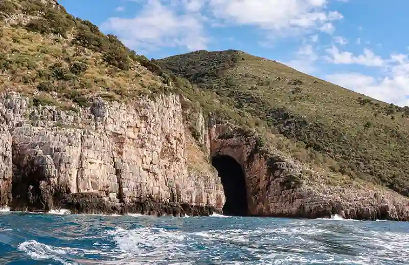 Entrada a la Cueva de Haxhi Ali con agua turquesa iluminando el interior de la cueva marina, Península de Karaburun