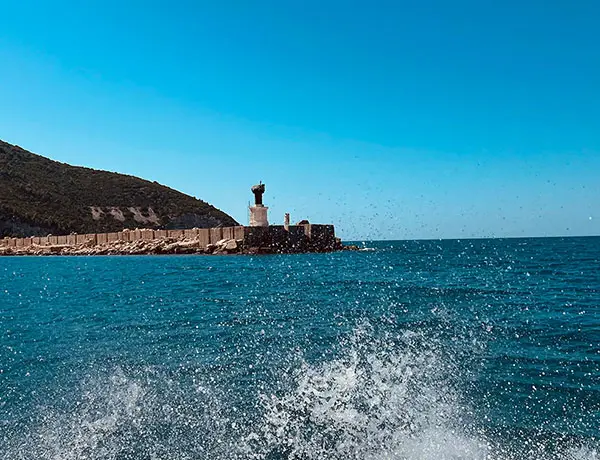 Vista del puerto y la costa de la Isla de Sazan desde una lancha rápida acercándose a la isla